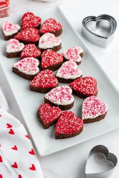 heart shaped cookies on a white plate with red sprinkles