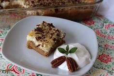 a piece of cake on a plate with whipped cream and pecans next to it