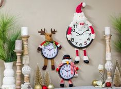 three clocks with santa claus and snowman on them are displayed in front of christmas decorations