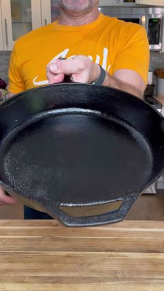 a man in an orange shirt is holding a frying pan