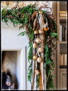 a christmas wreath with bells hanging from it's side next to a fire place