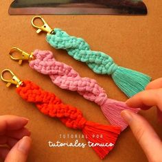 three crocheted tassels being held by someone's hand with scissors