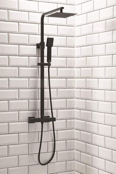 a black shower head in a white tiled bathroom