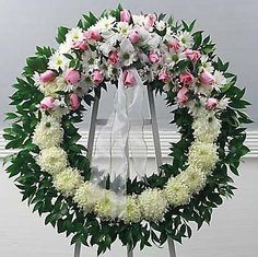 a white wreath with pink and white flowers