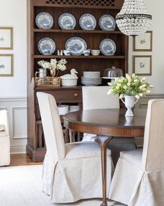 a dining room table and chairs with plates on the wall behind it, in front of a china cabinet