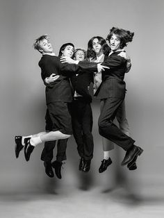 a group of people jumping in the air with one person holding his arms around another