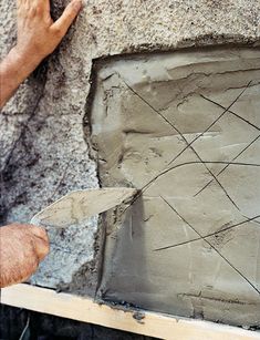 a man is using a pair of scissors to work on a cement block with lines drawn across it