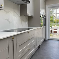 a kitchen with white cabinets and gray flooring next to a sliding glass door that leads to an outside patio