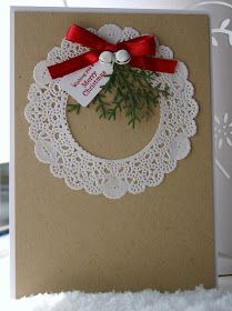 a christmas card with a red bow on the front and white doily around it