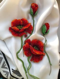 two red flowers on a white cloth with green stems