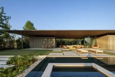 an outdoor swimming pool in the middle of a yard with lounge chairs and tables next to it