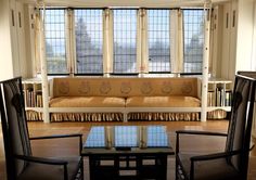 two chairs and a table in front of a window with bookshelves behind them