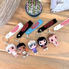 three key chains with cartoon characters on them sitting on a wooden table next to a vase