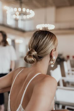 a woman sitting at a table with her back turned to the camera and wearing earrings