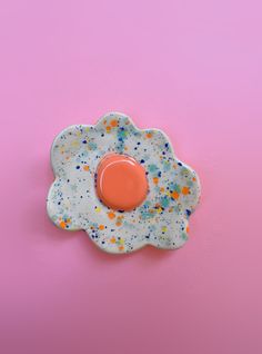 an egg shaped dish with sprinkles on pink and blue background, viewed from above