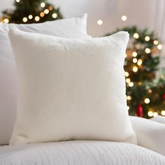 a white pillow sitting on top of a bed next to a christmas tree