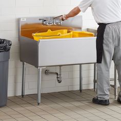 a man standing in front of a sink with yellow bins on the bottom and side