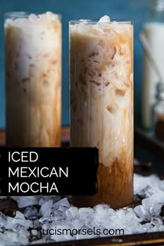 two tall glasses filled with iced coffee on top of ice covered ground next to bottles