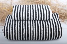 two black and white striped towels sitting on top of each other in front of some dry grass