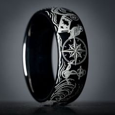 "Celebrate the maritime spirit of your high-seas adventures with this exquisite 8mm wide domed tungsten pirate-themed wedding band. Adorned with iconic nautical symbols including a menacing monsters of the deep, a weathered ship's wheel, a gleaming anchor, and a treasure chest overflowing with doubloons, each meticulously laser etched to create a lasting tribute to your seafaring memories.  Presented in a stunningly polished black tungsten band.  Our dedication to precision engraving ensures a flawless and sophisticated finish for this ring.  The black coating and engraved design provides stunning contrast from this detailed design.  Tungsten carbide, renowned for its extraordinary durability, promises enduring brilliance with just occasional cleaning. The interior of each ring bears the \ Persona Oc, Nautical Theme Wedding, Nautical Symbols, Pirate Wedding, Nautical Wedding Theme, Ring Bear, Country Rings, Black Wedding Band, Adventure Of The Seas