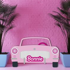 a pink car with bonmie written on the front parked next to potted palm trees