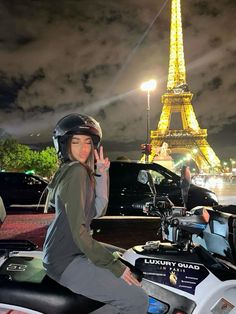 a woman on a motorcycle in front of the eiffel tower