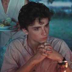 a man sitting at a table in front of a cake with lit candles on it