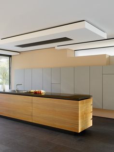 a modern kitchen with an island countertop and wooden cabinets in the center, along with large windows