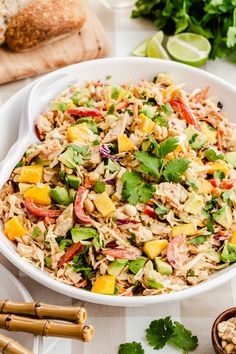 a white bowl filled with rice salad next to chopsticks and lime wedges