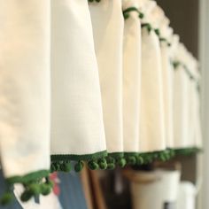 green pom - poms hang from the top of white curtains