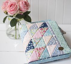 a pink rose is sitting next to a patchwork wallet