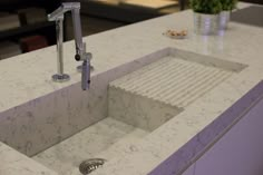 a white sink sitting under a faucet on top of a counter next to a potted plant