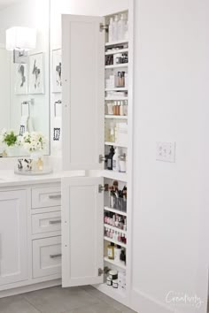 an open cabinet in the corner of a bathroom with white cabinets and drawers on both sides