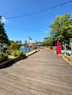 a woman in a red dress walking down a wooden walkway