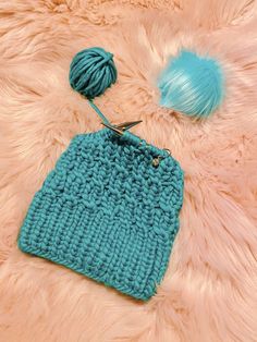 a crochet bag with two balls of yarn next to it on a fur surface