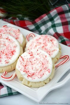 three cookies with white frosting and candy canes on a plate