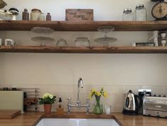 a kitchen with wooden counters and shelves filled with pots, pans, and flowers