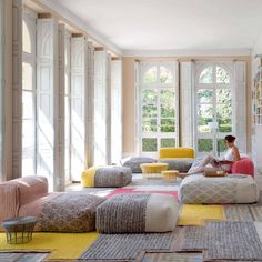 a woman sitting on top of a couch in a living room filled with lots of furniture