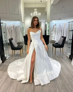 a woman standing in front of a mirror wearing a white dress with high slits