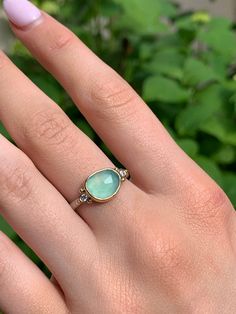 A seafoam green chrysoprase is set in 14k yellow gold a top a sterling silver seagrass band. Accented with small handmade gold beads. Approx stone size: 12mm x 10mm Approx stone weight: 2.9cts Mohs Hardness: 6-7 This one of a kind piece is handmade in Emily's Hudson Valley studio. If you have questions about sizing, shipping or need help deciding please reach out to us! Yellow Gold Chalcedony Jewelry For Anniversary, Yellow Gold Emerald Ring With Chrysoprase For Anniversary, Yellow Gold Chrysoprase Jewelry For May Birthstone, Chalcedony Yellow Gold Jewelry For Anniversary, Yellow Gold Chrysoprase Emerald Ring For Anniversary, Anniversary Yellow Gold Chrysoprase Jewelry, Sterling Silver Turquoise Ring In Yellow Gold, Chrysoprase Jewelry For Anniversary And May Birthstone, Fine Jewelry Chrysoprase Rings For Anniversary