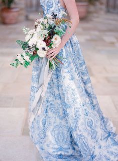 a woman in a blue and white dress holding a bouquet