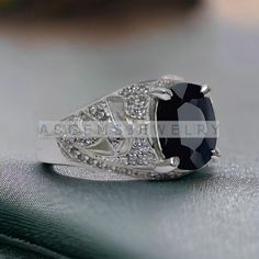 an oval black and white diamond ring on top of a piece of silver foil with diamonds around it