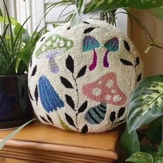 a decorative ball sitting on top of a wooden table next to potted greenery