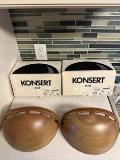 two wooden bowls sitting on top of a counter next to boxes with konseert logo