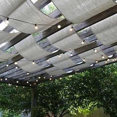 an outdoor covered patio with string lights strung from the ceiling and wood slats on the roof