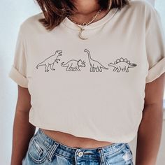 The cutest dinosaur family sweatshirt with all your favorite dinos like the t-rex, longneck and stegosaurus MATERIAL This t-shirt is everything you've dreamed of and more. It feels soft and lightweight, with the right amount of stretch. It's comfortable and flattering for both men and women.  ✨ Shirt sizes are Unisex, please refer to sizing chart in listing photos ✨ 100% combed and ring-spun cotton  ✨ Medium fabric weight CARE ✨ Machine wash: warm (max 40C or 105F) ✨ Do not iron ABOUT My love fo Dinosaur Family, Dinosaur Tshirt, Travel Sweater, Dinosaur Outfit, Dino Shirt, Dinosaur Shirt, Dinosaur Birthday Party, Cute Dinosaur, Women Shirt