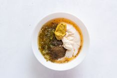 a white bowl filled with different types of food on top of a table next to a spoon