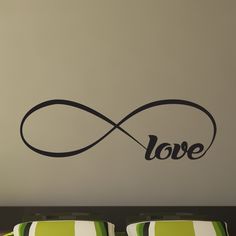 a bed room with a neatly made bed and a love wall sticker on the wall