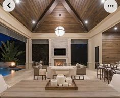 a living room filled with furniture and a fire place next to a swimming pool on top of a wooden floor