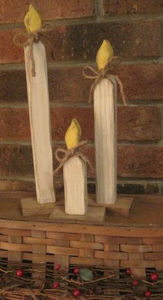 two white candles with yellow birds on them sitting next to each other in front of a brick wall